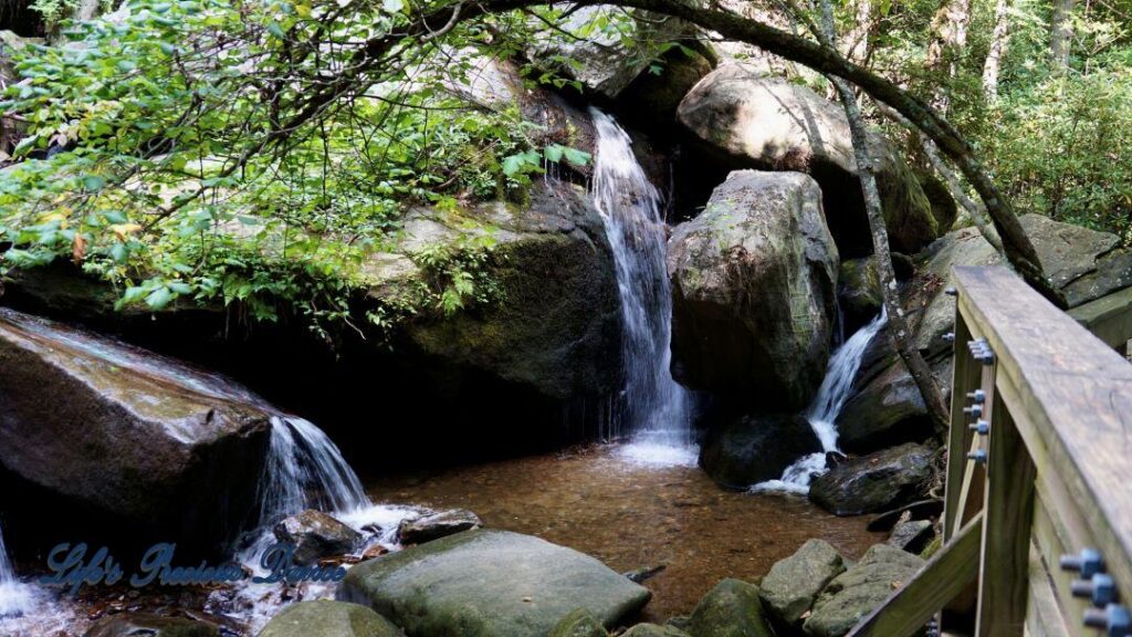 Waterfall running down and flowing between the rocks into a mountain stream.