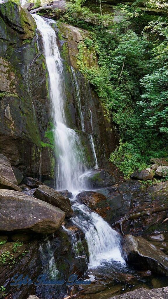 High Shoals waterfall flowing down the mountainside, over moss coverved rocks into the mountain stream below.