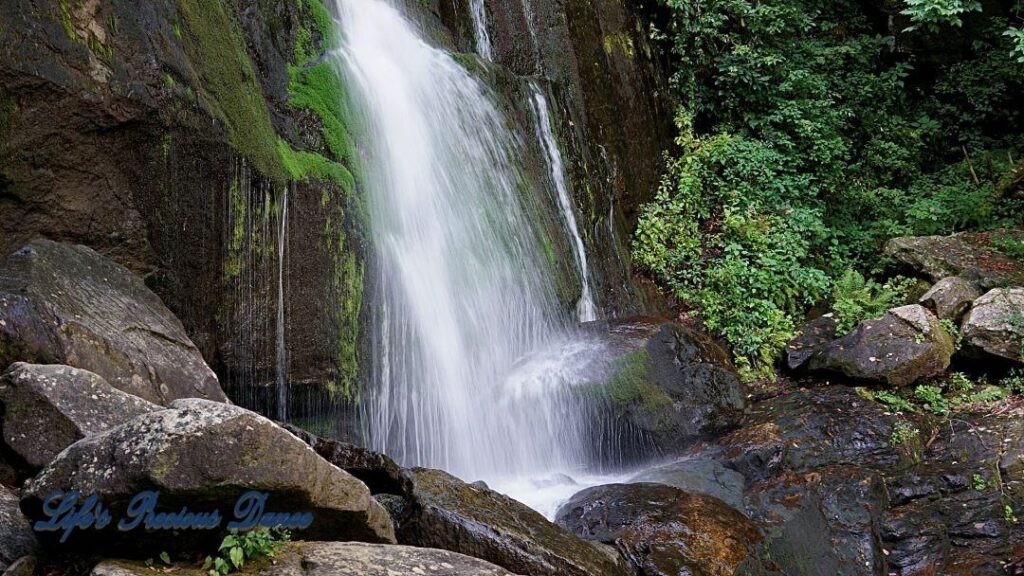 Close up of a waterfall, flowing down the mountainside, over moss covered rocks.