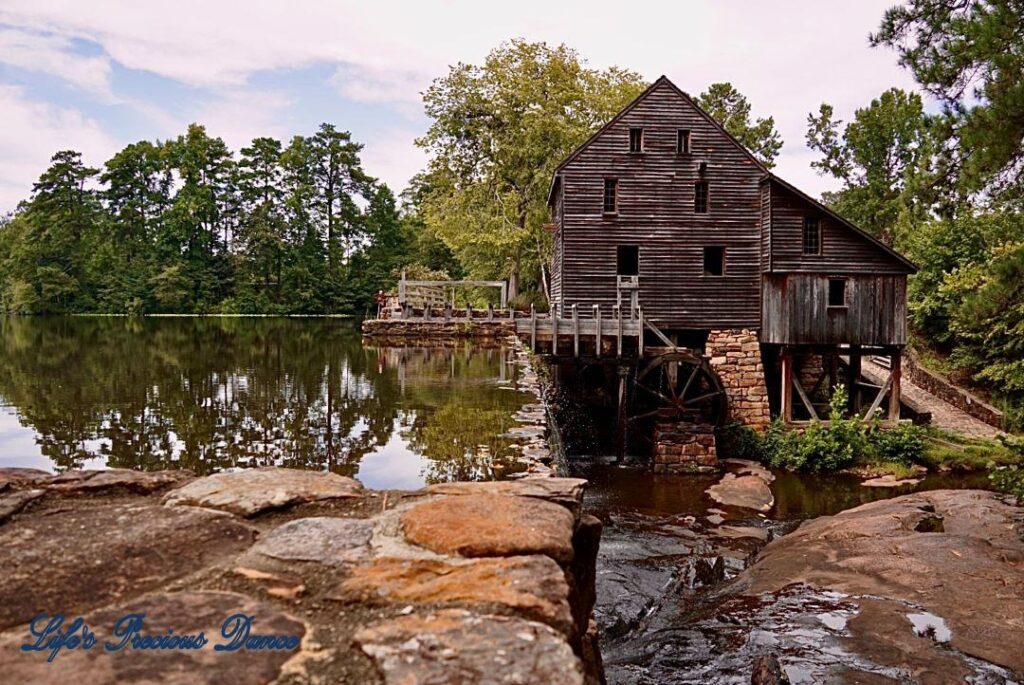 Historic Yates Mill beside the mill pond, with reflecting trees.