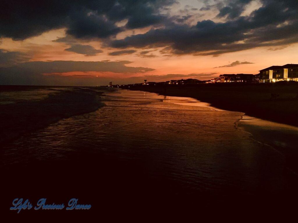 Sunset reflecting on the waves crashing onto Ocean Isle Beach with condos to the right.