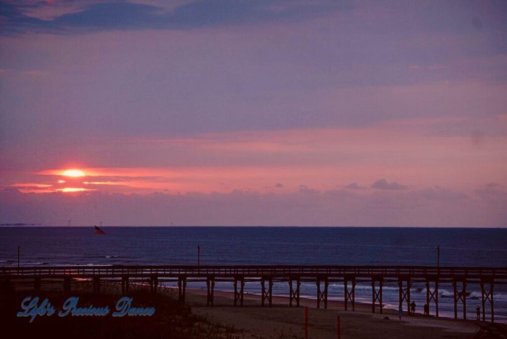 Sunrise at Ocean Isle Beach with pier and American flag in foreground