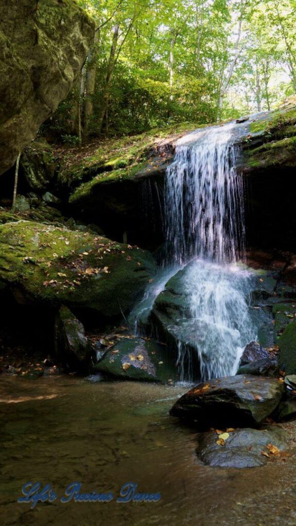 Otter Falls mountain stream spilling over a rock ledge into a pool below. Moss covered rocks, trees and colorful leaves