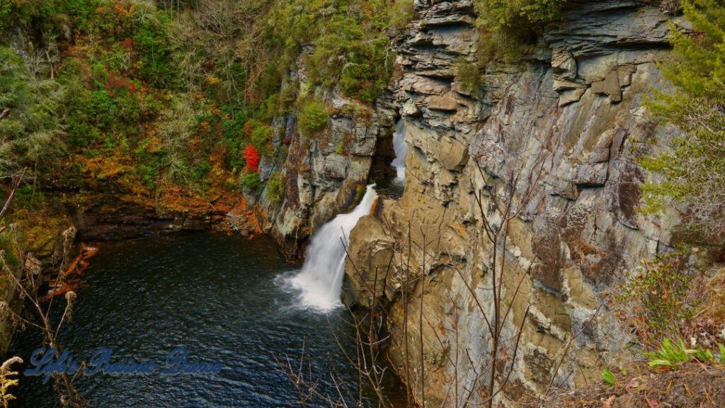 Linville Falls pouring down into the river basin. Colorful trees along the water.