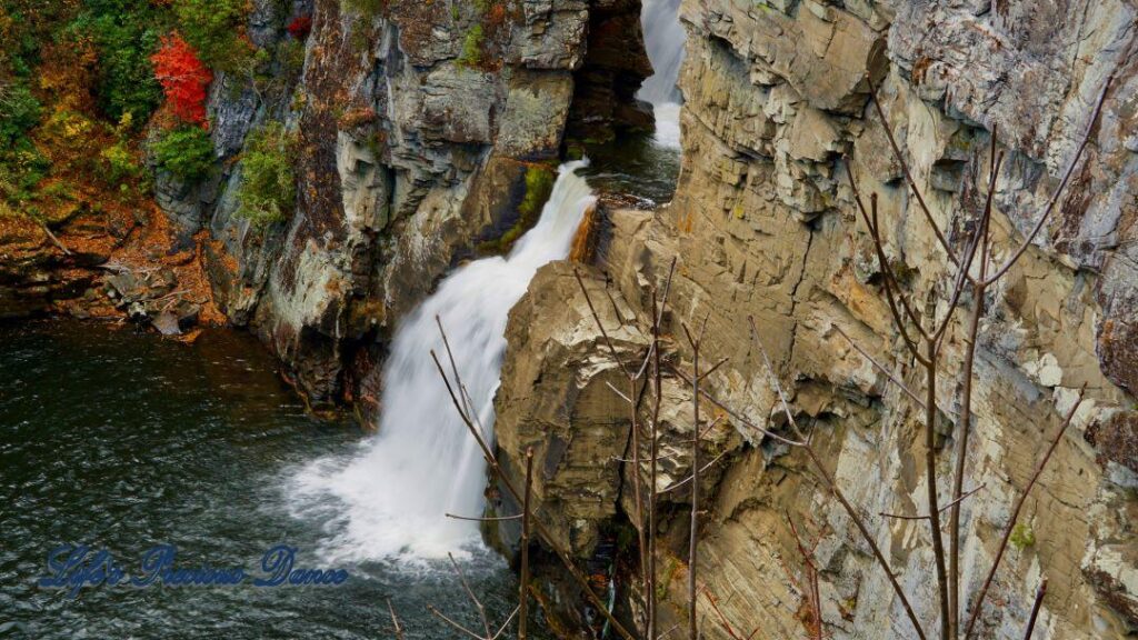 Linville Falls pouring down into the river basin. Colorful trees along the water.