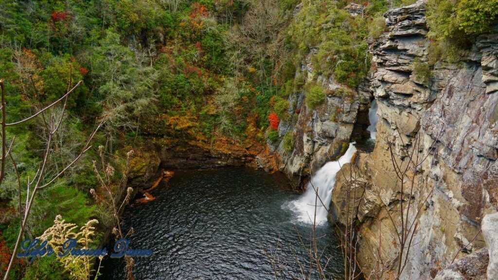 Linville Falls pouring down into the river basin. Colorful trees along the water.