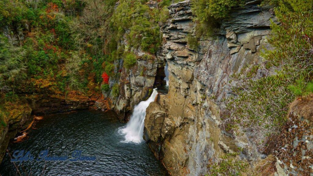 Linville Falls pouring down into the river basin. Colorful trees along the water.