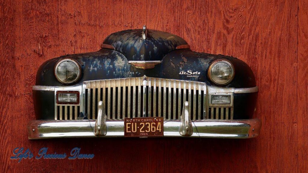 Close up of front end of classic DeSoto affixed to front of barn.