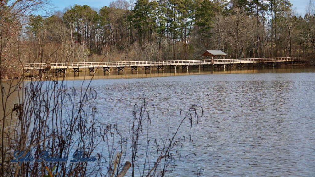 Yates MIll Pond. Wooden pedestrian bridge spanning the water in background.