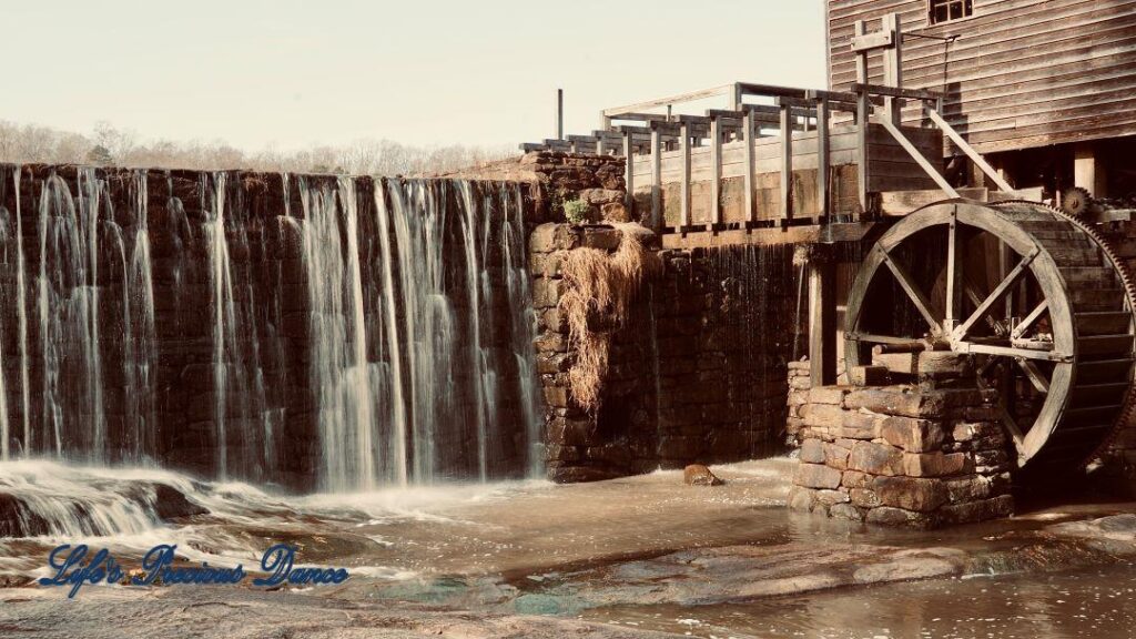 Pond water cascading over a rock wall beside Historic Yates Mill.