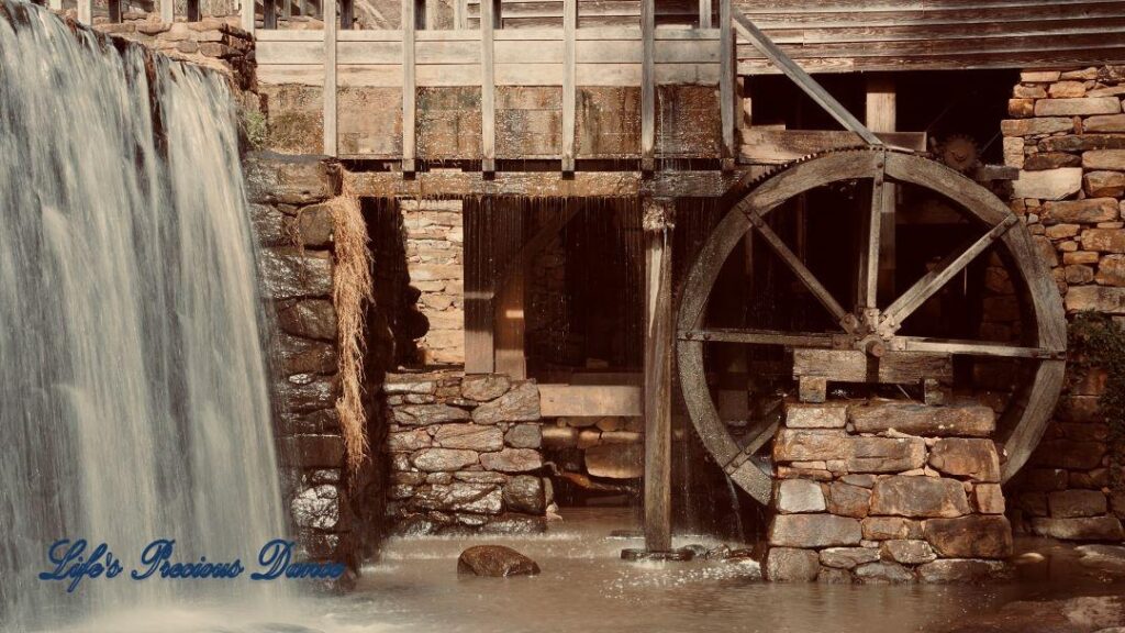 Pond water cascading over a rock wall beside Historic Yates Mill