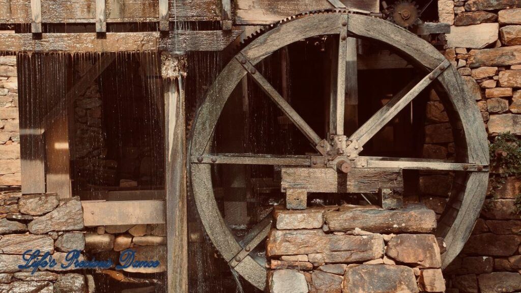 Water from pond flowing through wheel of an old mill.