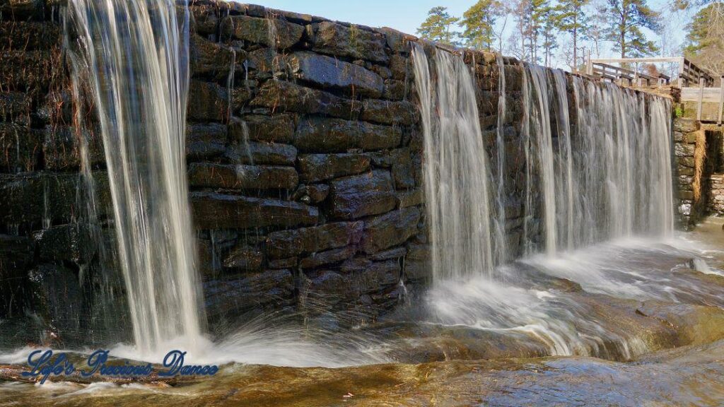 Water from mill pond cascading over rock wall into creek