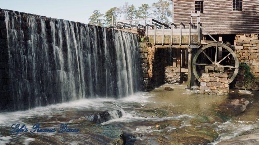 Water from pond cascading over rock wall into creek beside Historic Yates Mill.