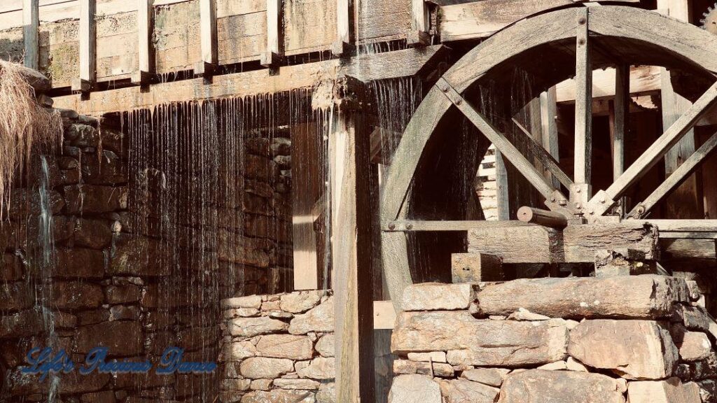 Water from pond flowing through wheel of an old mill.