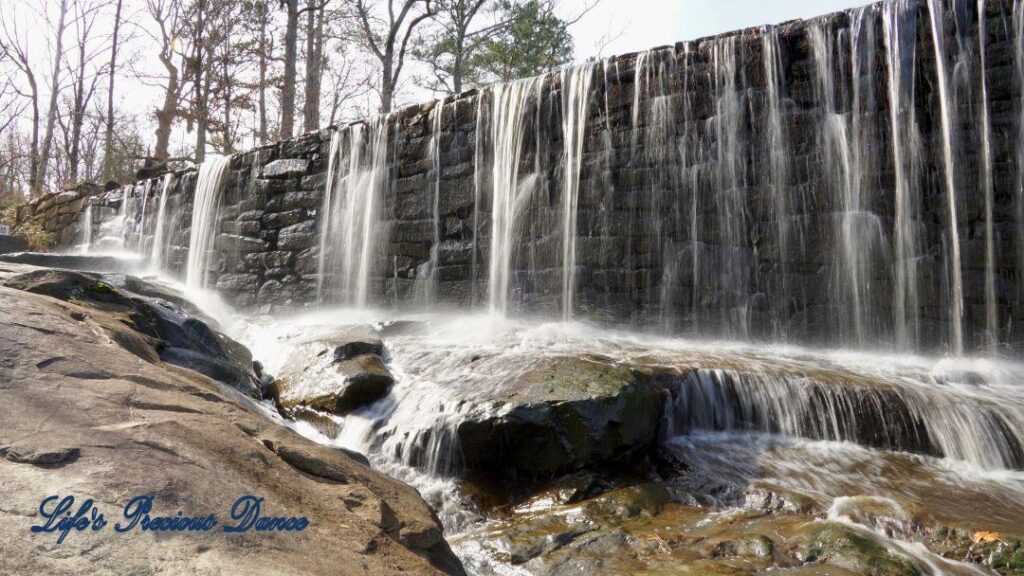 Water from mill pond cascading over rock wall into creek.