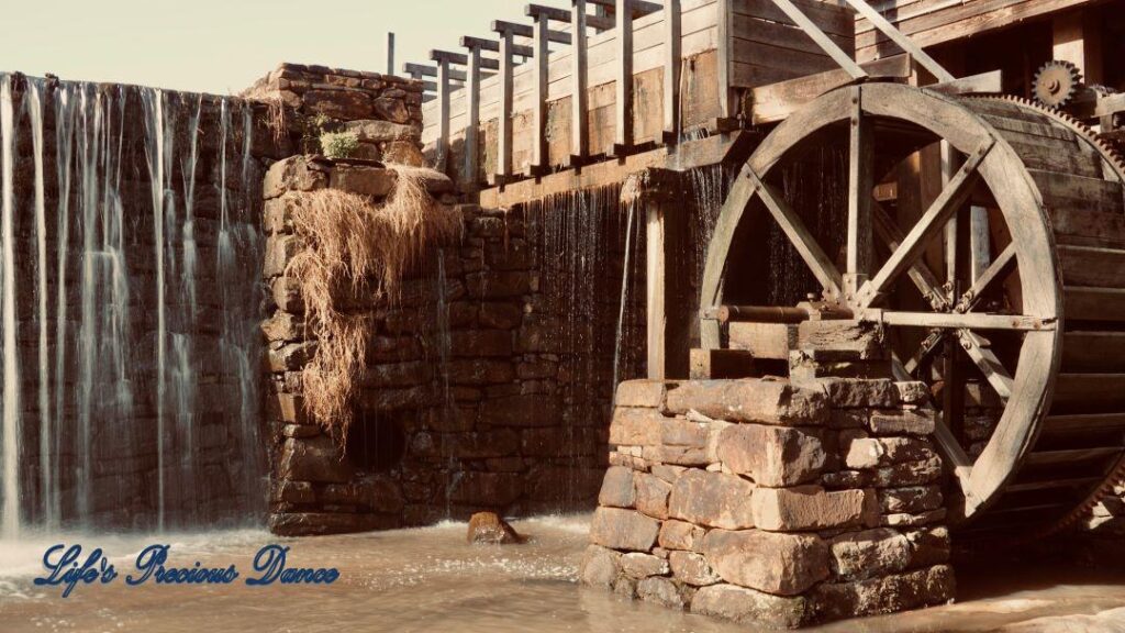 Pond water cascading over a rock wall beside an Historic Yates Mill.