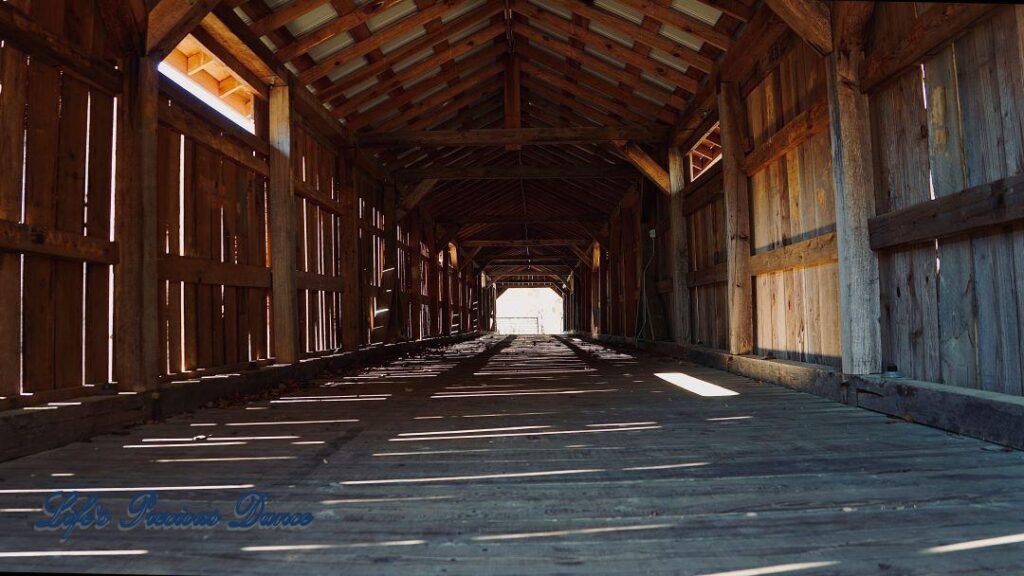 Inside of Ole Gilliam covered bridge, sun glistening through wood slats.