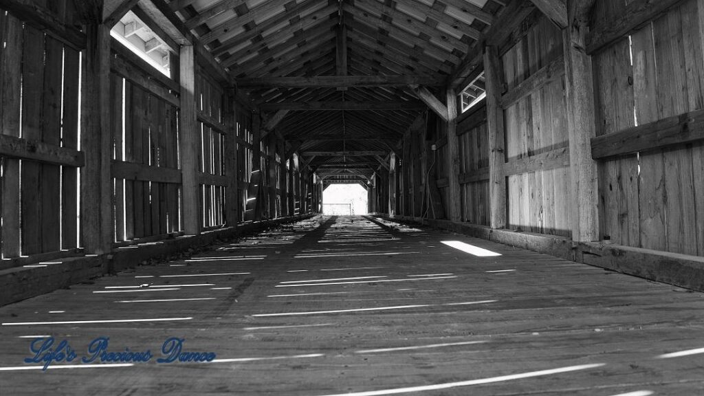 Black and white of Inside of Ole Gilliam covered bridge, sun glistening through wood slats.