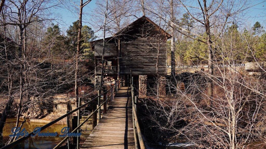 Small wooden walking bridge over creek, leading to mill.