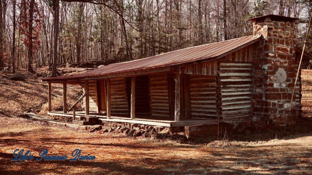 Front view of an old wooden cabin with a stone fireplace.