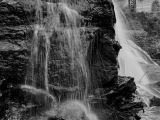 Black and white of Reedy Falls cascading over a rock face into the river below.