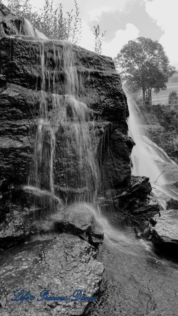 Black and white of Reedy Falls cascading over a rock face into the river below.