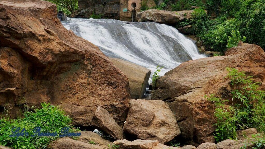 Reedy Falls cascading over rocks into the river below. Several boulders in the foreground.