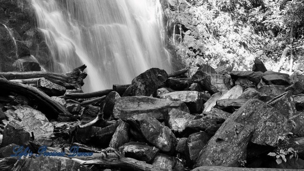 Black and white of Crabtree Falls cascading over rockface. Piles of rocks in foreground.