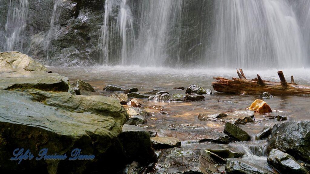 Crabtree Falls cascading down rockface into a pool of water. Rocks and a downed tree in foreground.