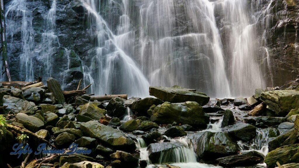 Crabtree Falls cascading down rockface into a pool of water. Moss covered rocks in foreground.