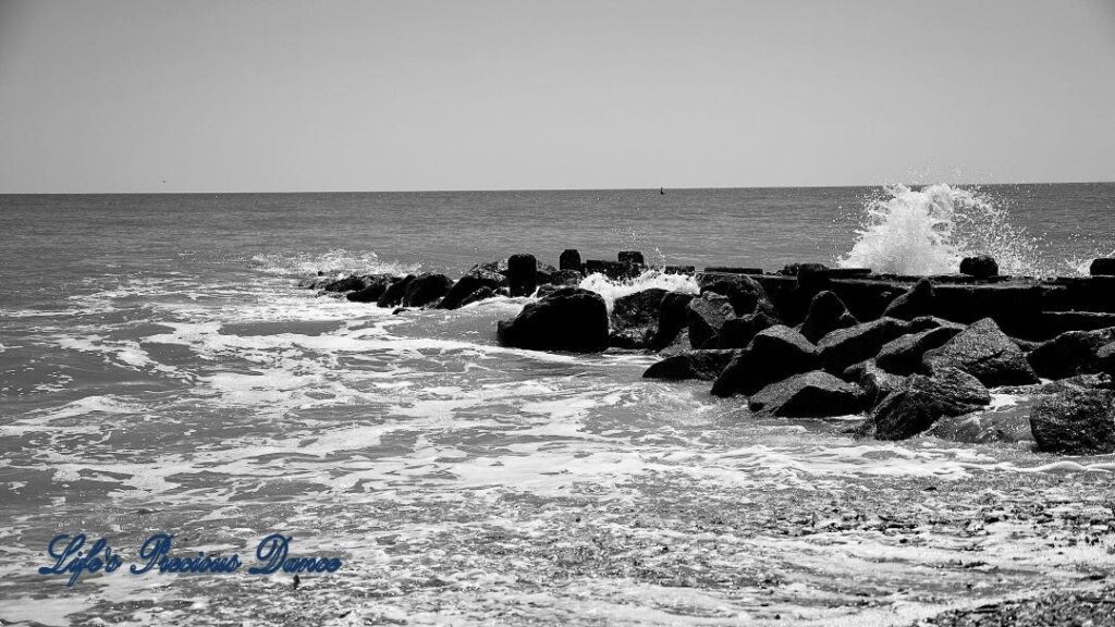 Black and white of waves crashing on a rock barrier at Edisto Beach.