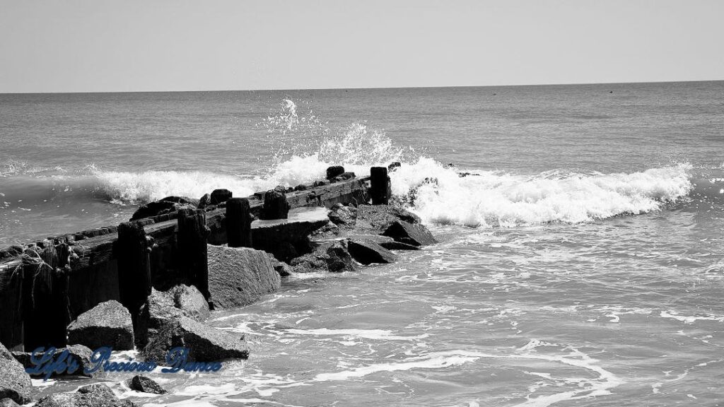 Black and white of waves crashing on a rock barrier at Edisto Beach.