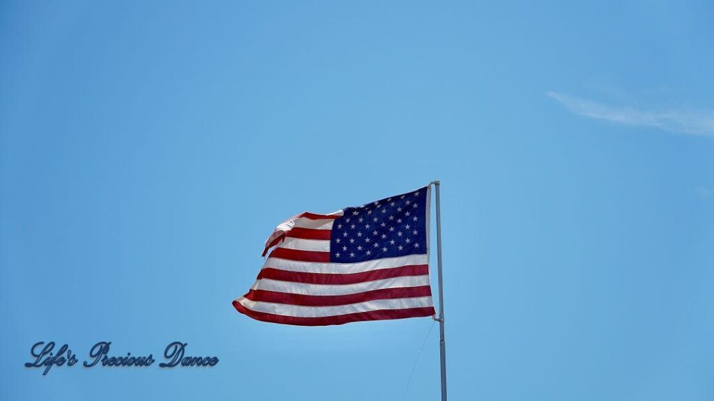 American Flag blowing in the wind against a Carolina blue sky backdrop.