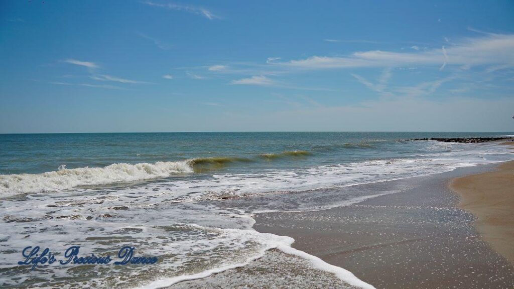 Waves crashing into the shore of Edisto Beach. A few passing clouds above.