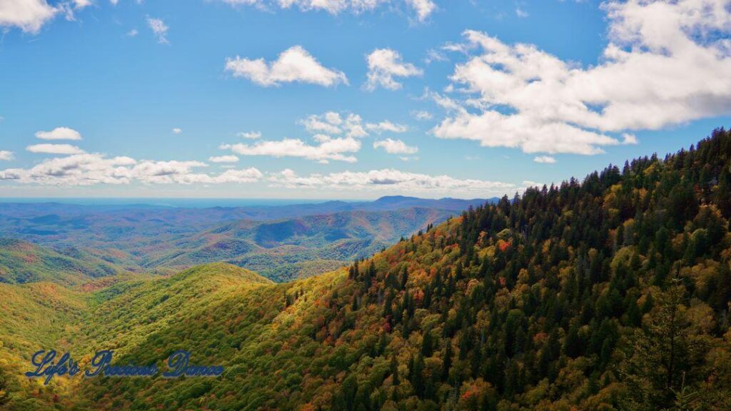 Landscape view of the colorful trees of the Blue Ridge Mountains. Passing clouds against a Carolina blue sky.