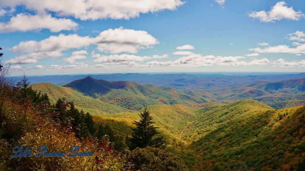 Landscape view of the colorful trees of the Blue Ridge Mountains. Passing clouds against a Carolina blue sky.