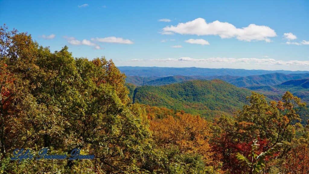 Landscape view of the colorful trees of the Blue Ridge Mountains. Passing clouds against a Carolina blue sky.