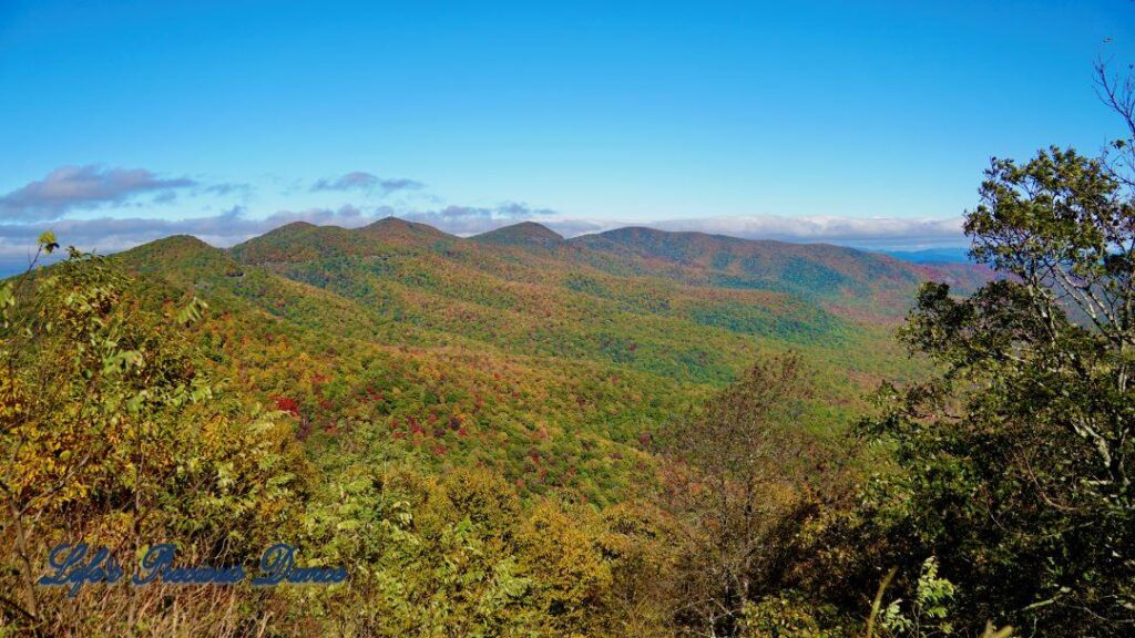 Landscape view of the colorful trees of the Blue Ridge Mountains. Passing clouds against a Carolina blue sky.