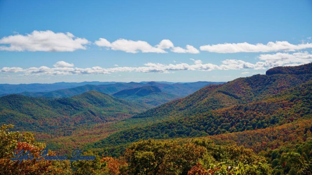 Landscape view of the colorful trees of the Blue Ridge Mountains. Passing clouds against a Carolina blue sky.