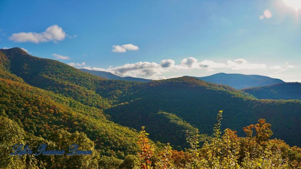 Landscape view of the colorful trees of the Blue Ridge Mountains. Passing clouds against a Carolina blue sky.