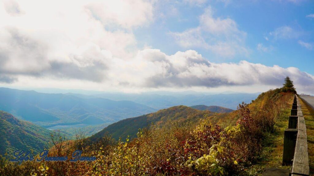 Landscape view of the colorful trees of the Blue Ridge Mountains. Passing clouds against a Carolina blue sky and fog in the valley.