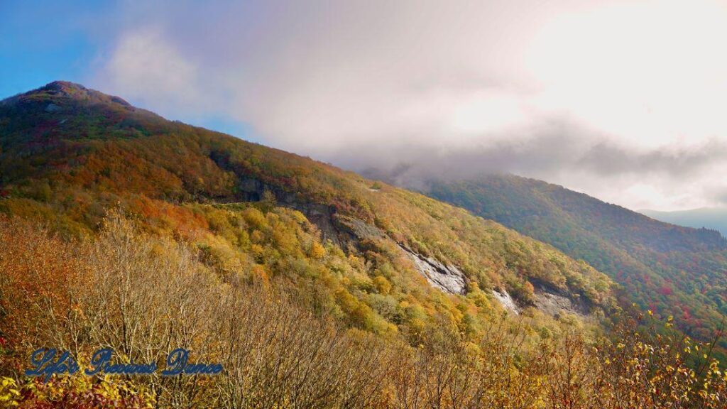 Landscape view of the colorful trees of the Blue Ridge Mountains. Clouds above and fog in the valley.