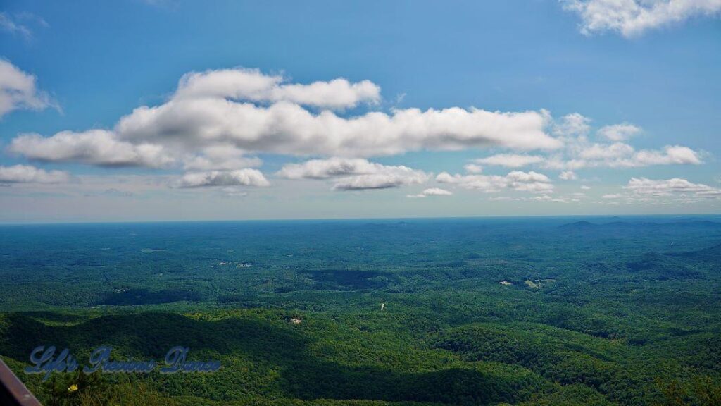 Landscape view from Caesar&#039;s Head of the valley of forest and mountain peaks below. Fluffy clouds drifting up above.