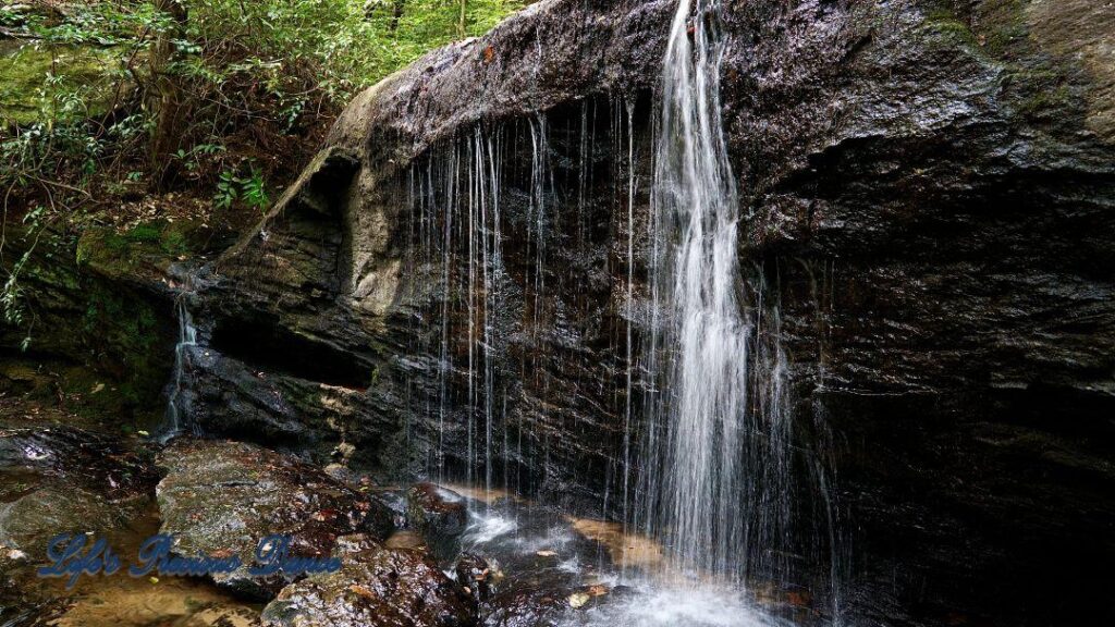 Waterfall spilling over a rock face into a mountain stream.