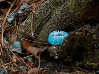 Painted rock in the nook of a tree that says "Be Happy"