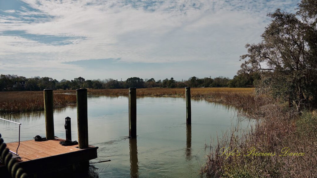 Pier posts reflecting in a marsh at Charles Towne Landing. Clouds reflecting in the water.