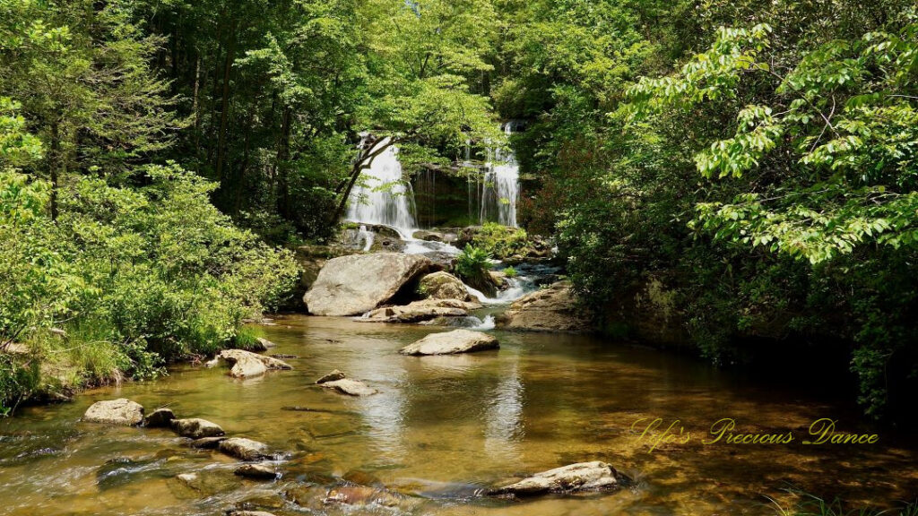 Long Creek Falls spilling over a rock face into a pool of water below and reflecting in the water.