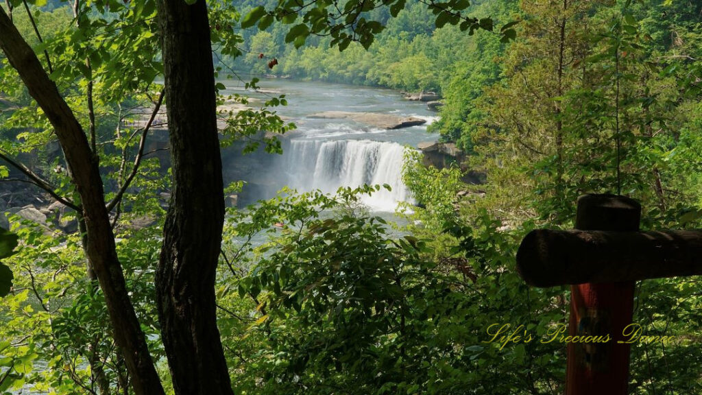 View from a trail overlook of Cumberland Falls, rapidly cascading over a cliff into the river basin below.