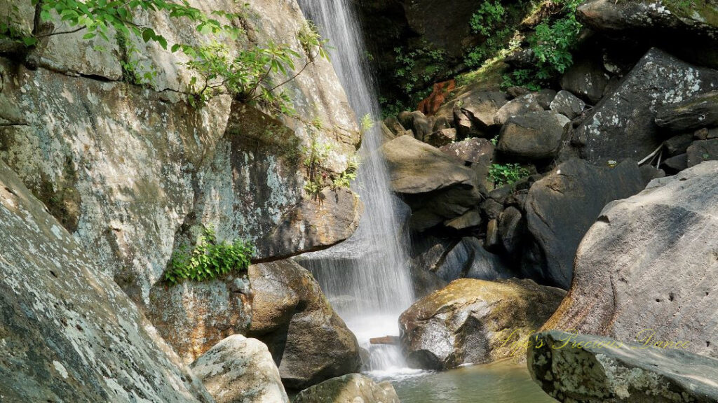 Eagle Falls spilling down the rockface wall, into a pool of water.